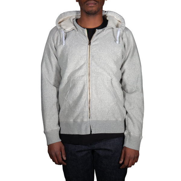 Person wearing a gray zip-up hoodie on a white background