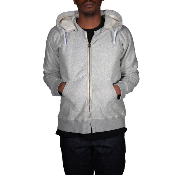 Person wearing a gray zip-up hoodie on a white background