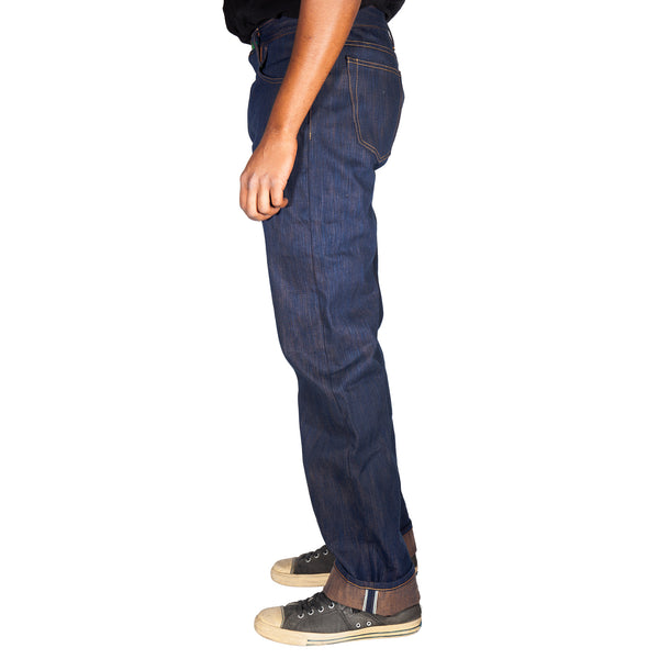 Person wearing blue jeans and brown shoes on a white background