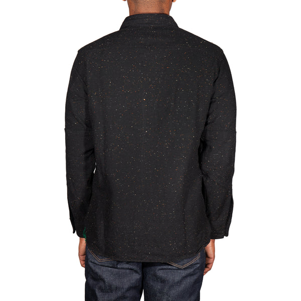 Person wearing a black speckled shirt on a white background