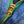 Close-up of a gold zipper pull on a green zipper against a blue denim background.