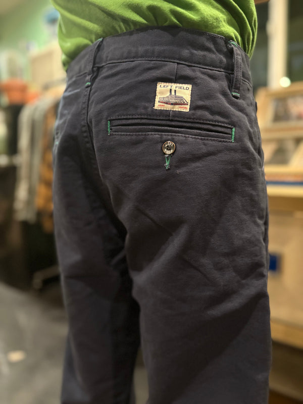 Dark pants with a brand label on the back pocket, worn by a person, in an indoor setting.