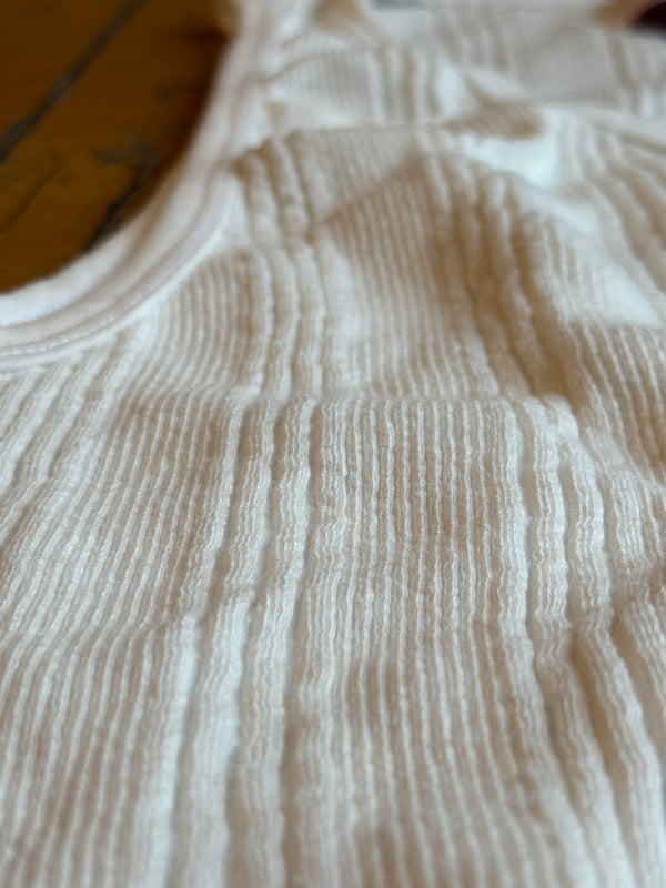 A white Japanese drop needle tank top with a slubby textured fabric,