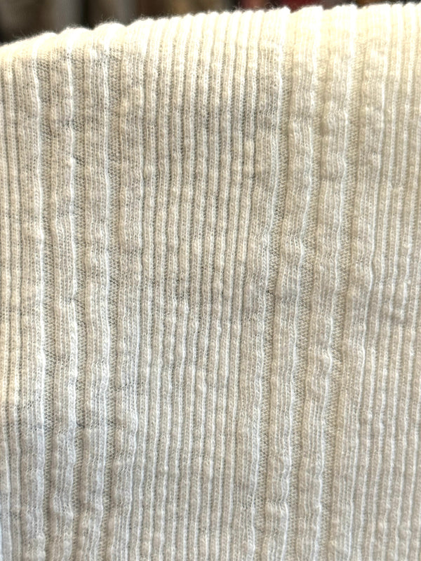 A white Japanese drop needle tank top with a slubby textured fabric,