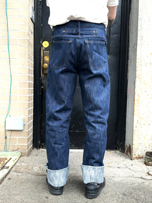 Person wearing blue jeans standing in front of a door.