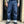Person wearing blue jeans and black shoes standing in front of a door.