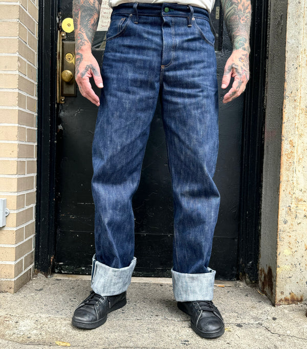 Person wearing blue jeans and black shoes standing in front of a door.