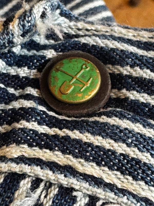 Close-up of a button with an anchor design on a striped fabric background