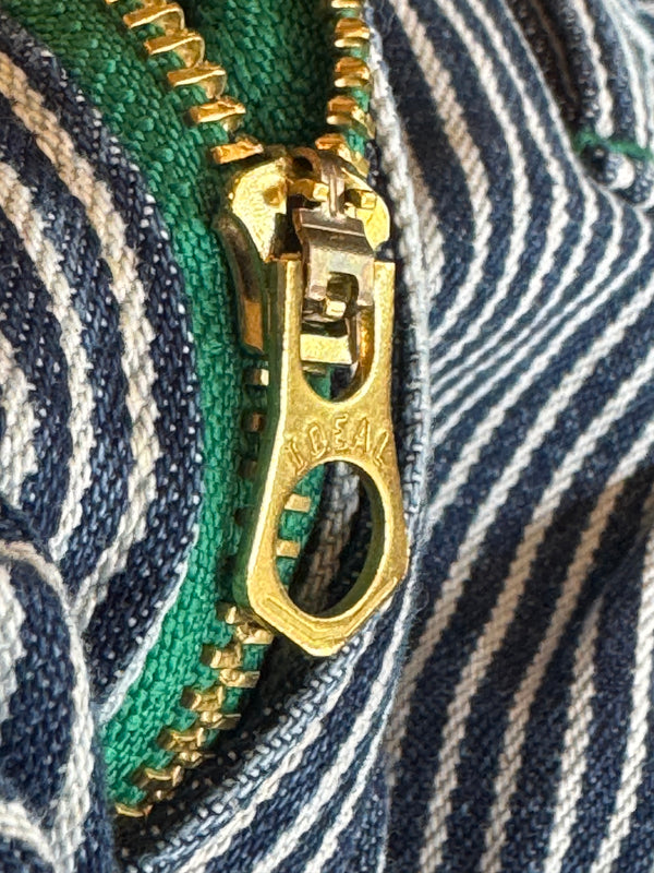 Close-up of a brass zipper pull on striped fabric