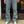 Person wearing hickory stripe pants and white sneakers standing in front of a door.
