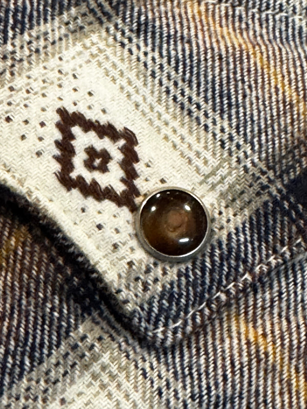 Close-up of a button on plaid fabric with a diamond pattern.