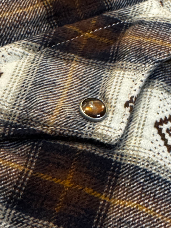 Close-up of a plaid fabric with a button, featuring a brand logo.