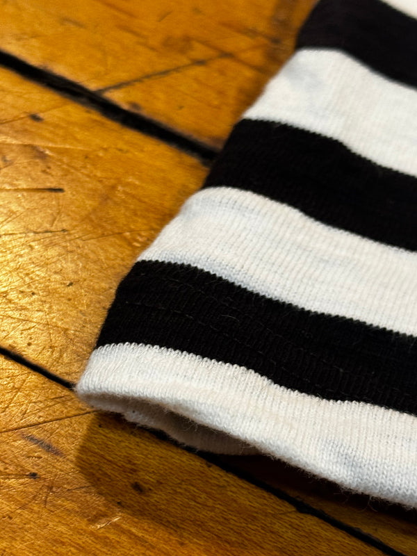 Close-up of a black and white striped sock on a wooden floor.