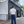 A man stands with his back to the camera wearing a white t-shirt and dark blue wide-leg jeans with rolled cuffs, positioned in front of a building with a 'LEFT FIELD WORKWEAR' sign.