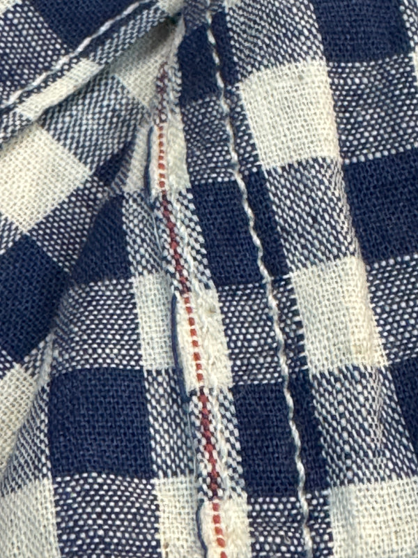 Close-up of blue and white checkered fabric with stitching detail selvedge