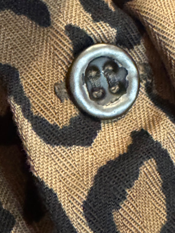 Close-up of a four-button fabric button on a brown and black leopard-print textile.