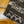 Close-up of a folded textile item showing two fabric patterns: a dark brown and gray herringbone camo section and a matching leopard-print section, laid on a rustic wooden surface.