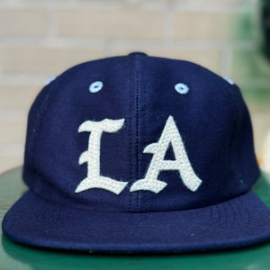 Navy blue cap with 'LA' logo on a green surface