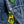 Close-up of a blue denim jacket with a gold zipper and green button.