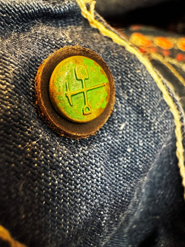 Close-up of a button with a green emblem on a denim fabric background