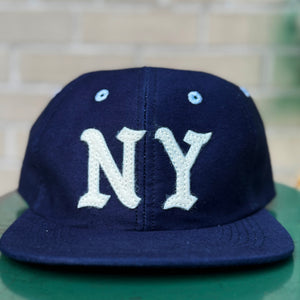 Navy blue cap with 'NY' on a green surface