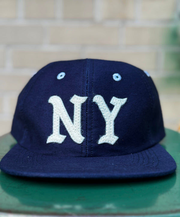 Navy blue cap with 'NY' on a green surface