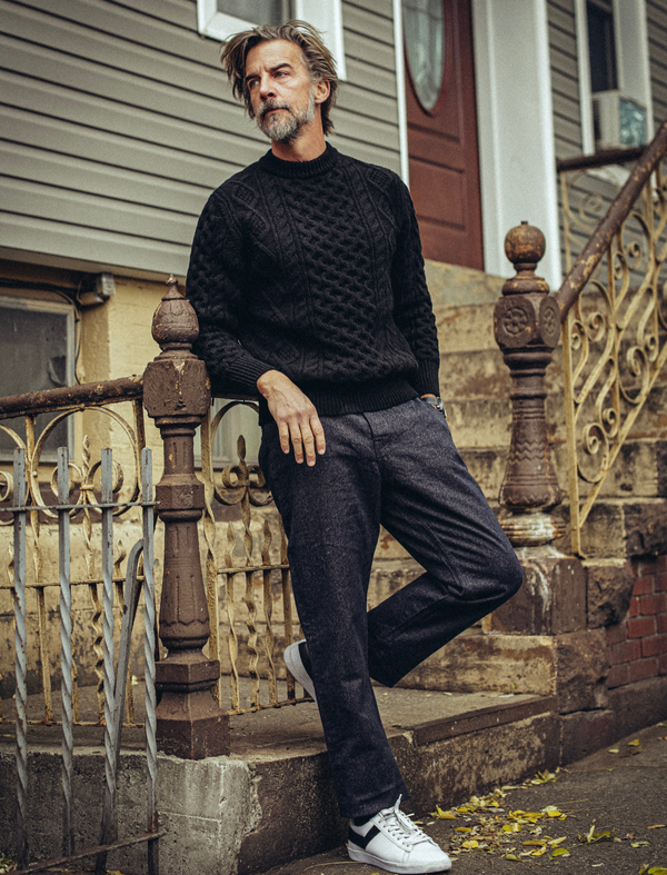 Man in a black sweater and pants standing on a set of stairs.