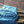 Blue textured fabric draped over a bamboo structure against a brick wall.