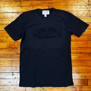 Black t-shirt with text on a wooden floor