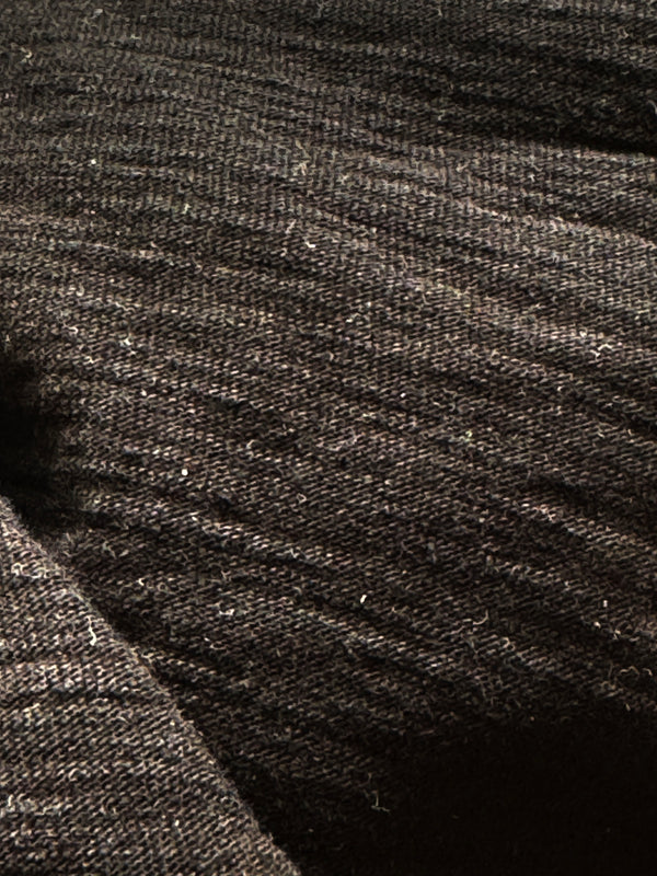 A black crew neck t-shirt with a tag visible at the neckline, laid flat on a plain surface.