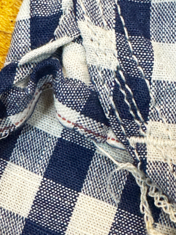 Close-up of blue and white checkered fabric with frayed edges selvedge