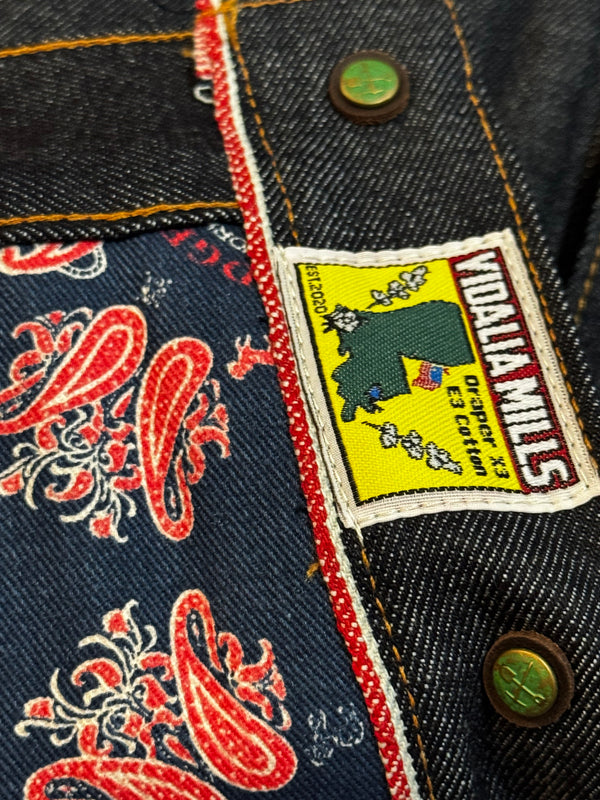Close-up of a denim jacket with a Vidal La Mills label and paisley pattern.