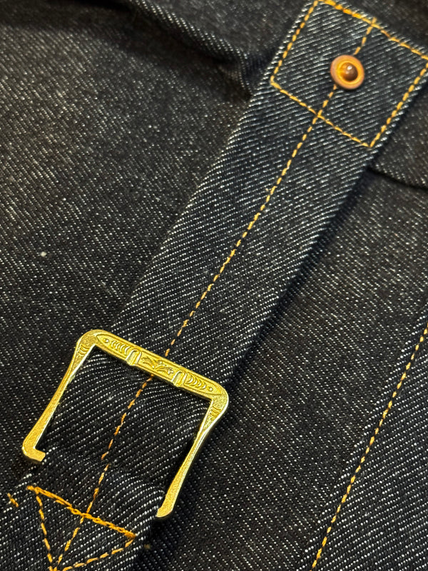 Close-up of a black denim belt with gold buckle and stitching