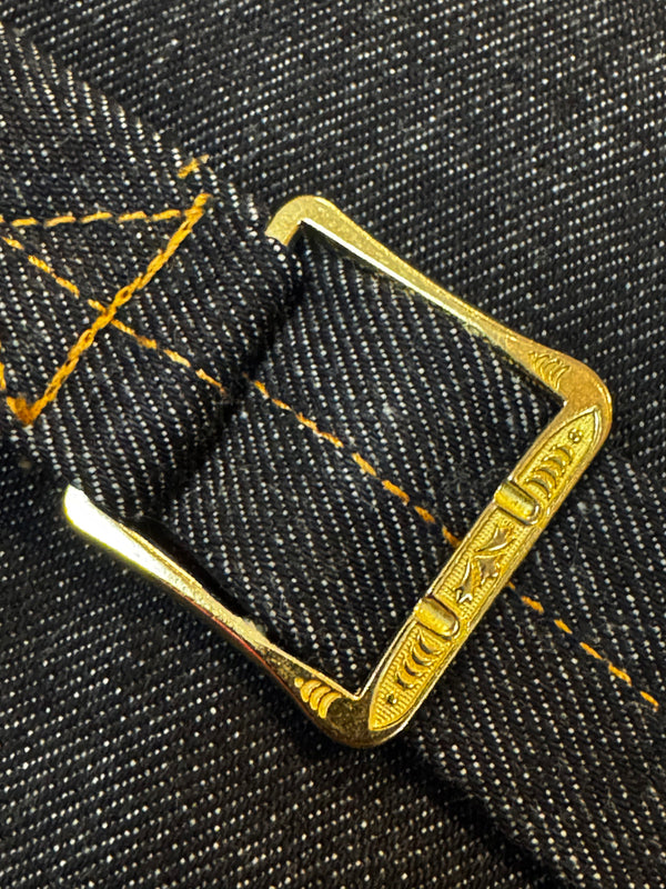 Gold metal buckle on black denim fabric