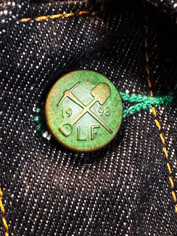 Green button with '1998' and 'OLF' on a denim background
