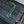 Close-up of dark denim fabric with green thread stitching