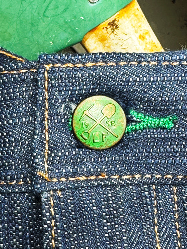 Green button with a logo on blue denim fabric