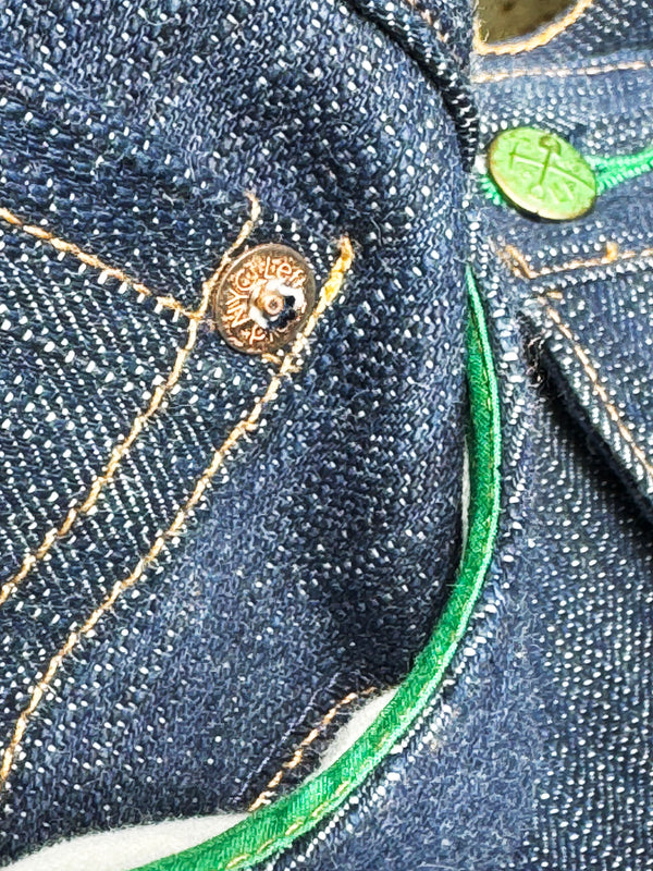 Close-up of a button on a denim fabric with green accents