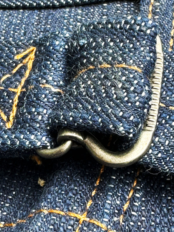 Close-up of a blue denim fabric with gold stitching and a zipper.