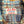 Close-up of a plaid shirt collar with a visible 'Left Field Sportswear New York City' brand label, showing a blue, brown, beige, and white plaid pattern against a yellow wooden background.