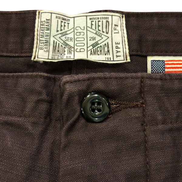 A pair of faded slate gray/black chinos with front and back patch pockets, high-rise waist, and long button front fly.