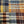 A close-up of a woven plaid fabric with a multicolor pattern featuring navy, orange, brown, beige, and yellow stripes.