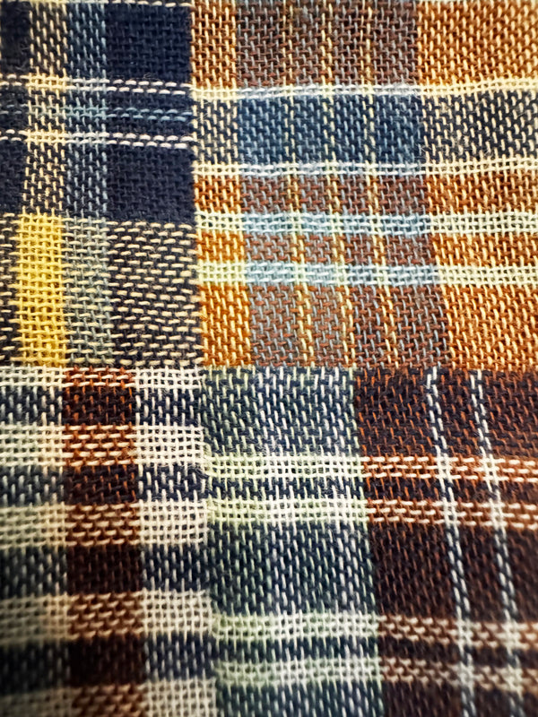 A close-up of a woven plaid fabric with a multicolor pattern featuring navy, orange, brown, beige, and yellow stripes.