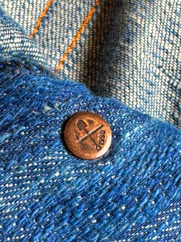 A pair of natural indigo dyed denim jeans with visible texture and a classic design.