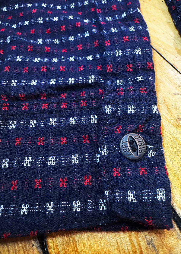 Close-up of a navy blue fabric with red and white patterns on a wooden surface
