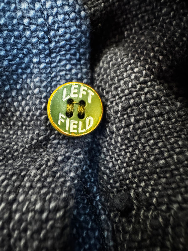 Button with 'LEFT FIELD' text on a textured fabric background