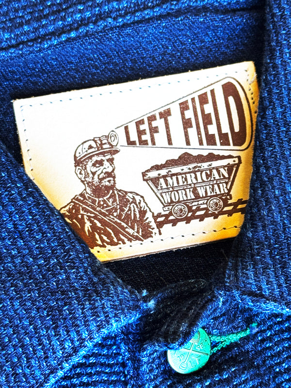 Close-up of a 'Left Field American Work Wear' label on blue fabric.