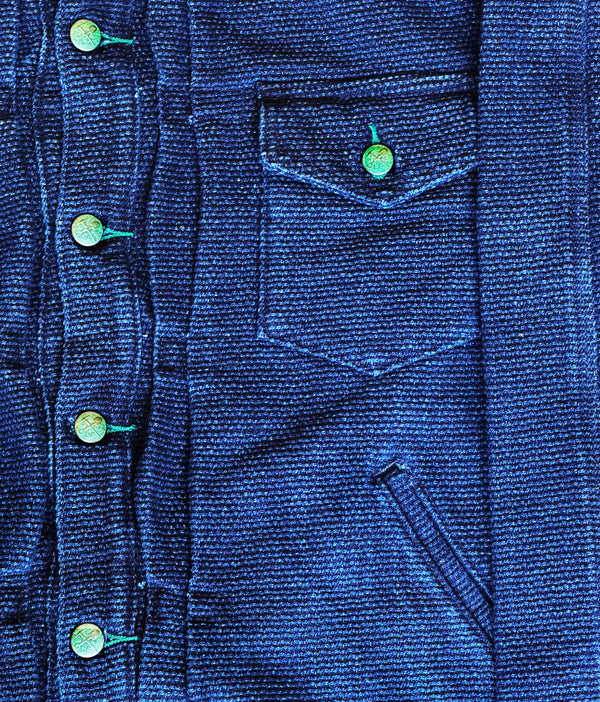 Close-up of a blue denim jacket with buttons and a pocket.