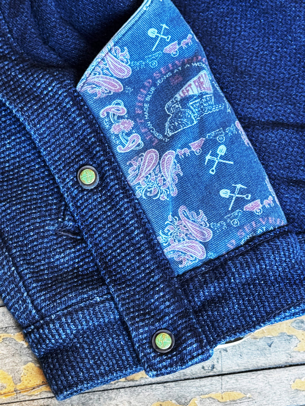 Close-up of a blue denim jacket with a patterned label on a wooden surface