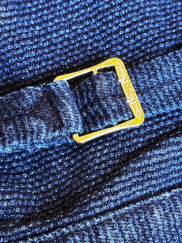 Close-up of a blue textured fabric with a gold buckle.